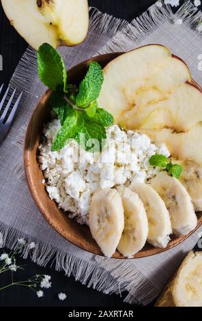 concept de nourriture saine, vue de dessus, fromage cottage avec banane, pomme et une branche de menthe sur une table noire Banque D'Images