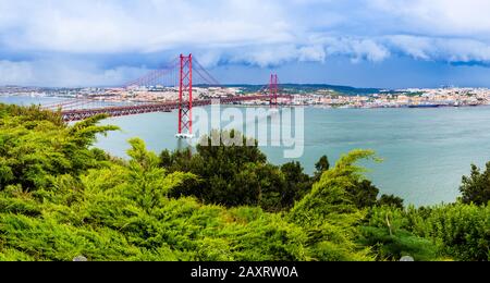 Lisbonne, Portugal - Paysage du pont du 25 avril sur l'estuaire du Tage et les gratte-ciel de Lisbonne, vu des collines d'Almada avec dramatisation Banque D'Images