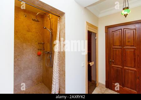 Douche dans le sauna. Carreaux beige. Joli et confortable. La porte du hammam et la porte d'entrée sur la droite. Banque D'Images