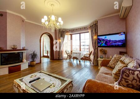 Salle de style classique avec deux canapés, table basse, TV. Une table ronde et deux chaises près de la fenêtre. Couleur beige. Table blanche avec jambes incurvées. Bois Banque D'Images