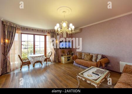 Salle de style classique avec deux canapés, table basse, TV. Une table ronde et deux chaises près de la fenêtre. Couleur beige. Table blanche avec jambes incurvées. Bois Banque D'Images