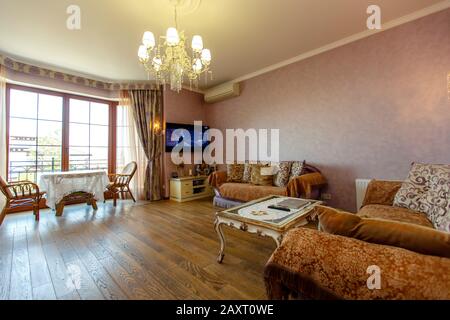 Salle de style classique avec deux canapés, table basse, TV. Une table ronde et deux chaises près de la fenêtre. Couleur beige. Table blanche avec jambes incurvées. Bois Banque D'Images