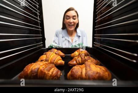 Une femme gaie prend de délicieux croissants croustillants au four Banque D'Images