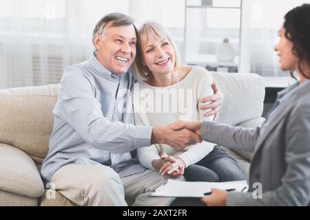 Femme realtor à la main heureuse couple d'âge mûr au bureau Banque D'Images