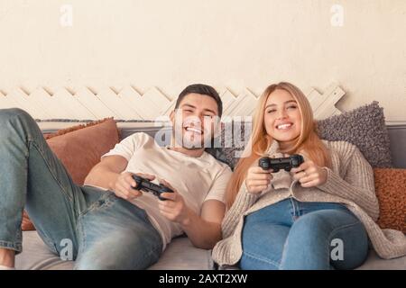 Heureux couple tenant des joysticks et jouer au jeu vidéo Banque D'Images