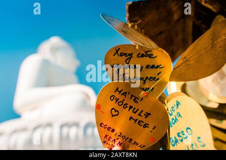 Nakkerd Hill, Phuket/Thailand-15December2019: Des cloches de prière en forme de coeur doré pendent ensemble dans une rangée avec des notes spirituelles de personnes écrites sur eux Banque D'Images