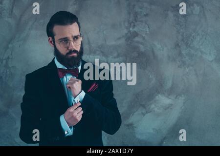 Portrait de son sympathique sympathique gars bien habité élégant barbu portant des poignets de fixation tux se préparant à l'événement solennel isolé sur le béton gris Banque D'Images