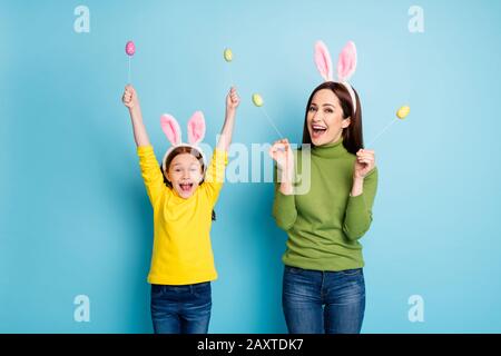 Portrait de jolies jolies jolies filles gaies joyeux maman tenant dans les mains œufs bâtons ayant l'amusement isolé sur brillant vif brillant vif brillant dynamique Banque D'Images