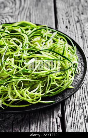 pâtes courgettes fraîches, nouilles sur une plaque noire sur une table en bois rustique, vue verticale depuis le dessus, gros plan Banque D'Images