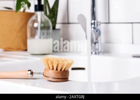 Brosse à vaisselle en matériau naturel sur plan de travail blanc gros plan. Banque D'Images