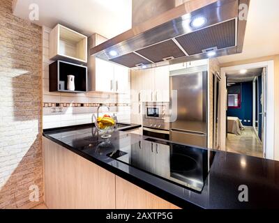Nouvelle cuisine élégante et lumineuse avec des armoires en bois à côté du salon. Intérieur spacieux et moderne entièrement équipé avec bureau en pierre, céramique St Banque D'Images