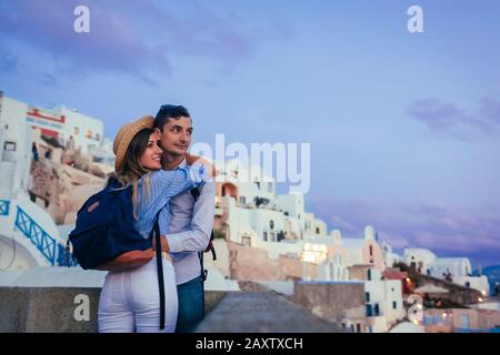 Saint Valentin à Oia. Couple amoureux de lune de miel sur l'île de Santorin Grèce au coucher du soleil profitant du paysage Banque D'Images