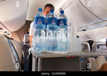 Un membre de l'équipage de cabine avec un chariot pour boissons nautiques livre des rafraîchissements aux passagers Economy dans leurs sièges sur un avion Bombardier passagers avion / avion / avion / avion / avion. (112) Banque D'Images