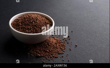 Pile de poudre de cacao dans un bol sur fond noir Banque D'Images