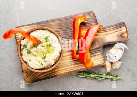 Vue sur la couche plate du plat de trempage Hummus aux légumes recouvert d'huile d'olive servie avec des tranches de poivron rouge Banque D'Images
