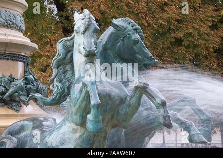 Sculptures de chevaux galopants en charge à travers les jets d'eau de la monumentale Fontaine de l'Observatoire dans le jardin Marco Polo. Paris, France. Banque D'Images