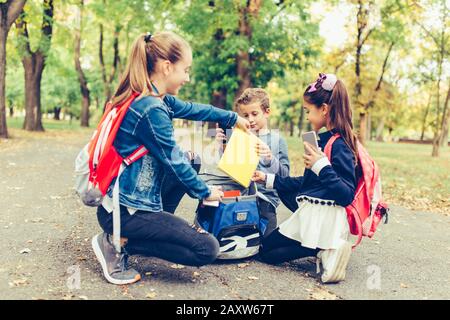 Retour à l'école. Les enfants avec des sacs à dos ont du plaisir, de parler, de lire un livre.Groupe d'écoliers élémentaires ayant une discussion sur les devoirs pendant que goi Banque D'Images