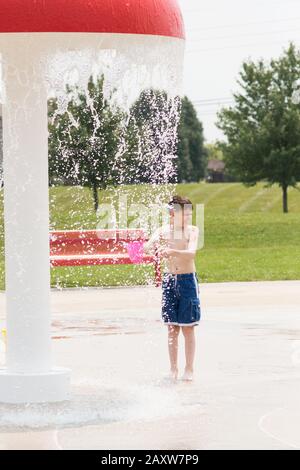 Un garçon de onze ans se mouille dans un parc d'attractions lors d'une journée d'été à Carmel, Indiana, États-Unis. Banque D'Images