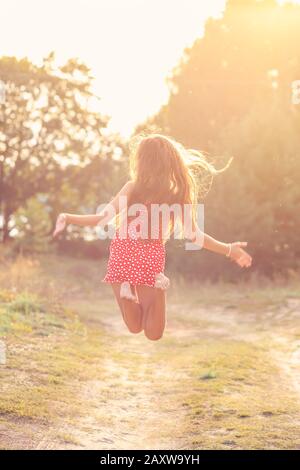 Portrait de La Belle jeune fille est sauter dehors au coucher du soleil d'été Banque D'Images