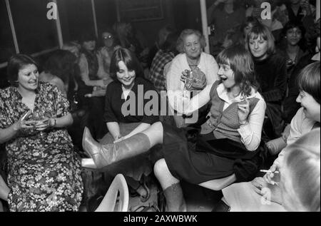 Hen Party 1970 Londres Royaume-Uni. Les jeunes femmes de groupe et une dame âgée de haut niveau qui regarde tout le monde s'amuser. Boire, montrer une jambe tirant sur un visage. Soirée fille. 1979 HOMER SYKES Banque D'Images