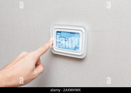 Une main d'homme appuie sur un bouton du tableau de commande d'équipement de climatisation Banque D'Images