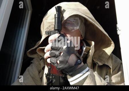 Homme armé portant une capuche donnant sur la fenêtre, portrait extérieur Banque D'Images
