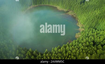 Drone vue aérienne du lagon de 'Lagoa do Canario' entouré d'une forêt verte située à Sao Miguel, Açores, Portugal. Banque D'Images