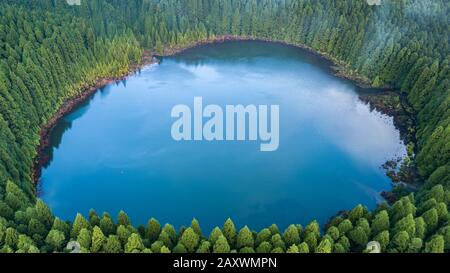 Drone vue aérienne du lagon de 'Lagoa do Canario' entouré d'une forêt verte située à Sao Miguel, Açores, Portugal. Banque D'Images