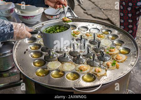 Femme faisant de petites crêpes vietnamiennes sizzled - Banh Khot Vung Tau Banque D'Images