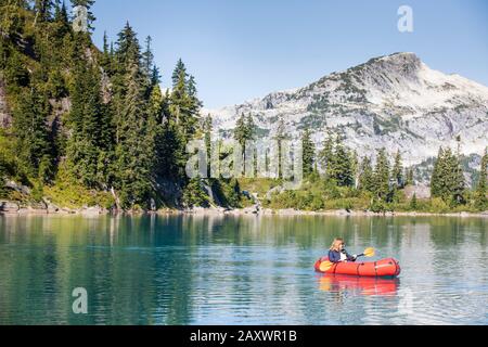 Femme à la retraite en train de paddle sur un lac de montagne isolé. Banque D'Images