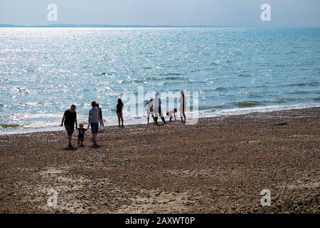 Les gens qui apprécient la plage au bord de l'eau en début de soirée en été. Belle Plage, West Sands Selsey, West Sussex, Angleterre. Banque D'Images