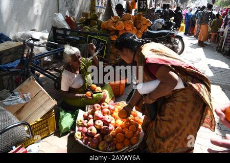 Une vieille dame indienne qui vend des oranges dans une rue animée de Madurai, Tamil Nadu, Inde Banque D'Images