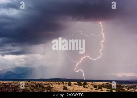 Un coup de foudre atterrit dans les contreforts des pics de San Francsico alors qu'un orage de mousson traverse le monument national de Wupatki, en Arizona Banque D'Images