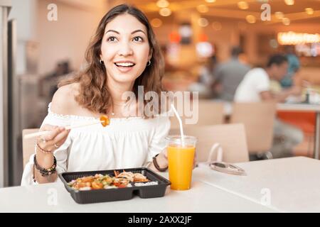 Une femme asiatique mangeant une boite à bento japonaise dans la cour alimentaire Banque D'Images