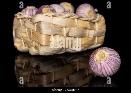 Beaucoup d'ail violet frais entier à une gousse dans le panier de pain isolé sur le verre noir Banque D'Images