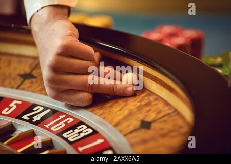 Main d'un casino avec une balle sur une roulette au cours d'une partie dans un casino. Banque D'Images