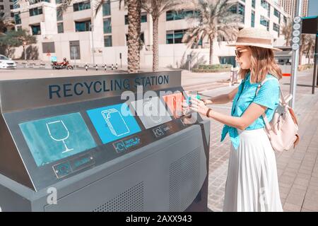 Une fille trie et jette les ordures dans une station de rue pour le recyclage des déchets plastiques. Concept de conservation de l'environnement Banque D'Images