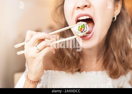 Une fille mangeant des sushis avec des baguettes tout en prenant un déjeuner Bento dans le terrain de restauration Banque D'Images