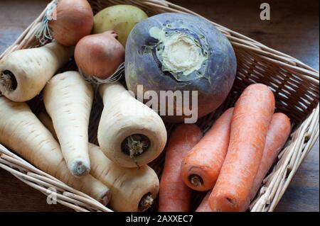 Panier en osier de légumes frais à base de racines, y compris panais, carottes, navets et oignons exposés à un mearket Banque D'Images