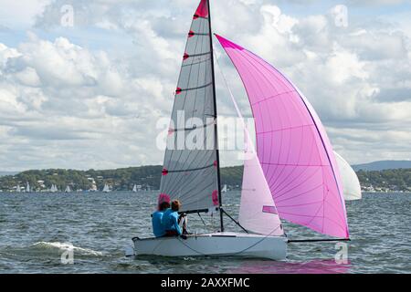 Deux écoliers naviguant sur un petit voilier avec un spinnaker rose dynamique entièrement déployé pour s'amuser et en compétition. Travail d'équipe par des marins juniors en course sur s Banque D'Images