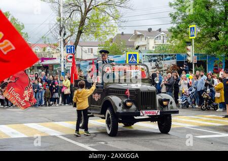 Anapa, Russie - 9 mai 2019: Les enfants donnent des fleurs aux anciens combattants conduisant une voiture militaire restaurée lors du défilé de victoire à Anapa Banque D'Images