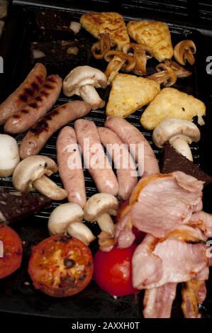 Petit déjeuner anglais sain sur une grille avec bacon, tomate, champignons, saucisses et tranches de fromage grillé Banque D'Images