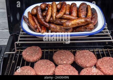 Hamburgers et saucisses sur un barbecue extérieur Banque D'Images