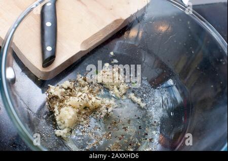 Gousses d'ail frais pelées et herbes au fond d'un bol de mélange de verre transparent à incorporer comme ingrédients et assaisonnement pendant la cuisson de Banque D'Images