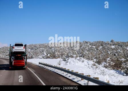 La remorque transporte les voitures sur la route d'hiver de la route avec des paysages de neige dans les montagnes Banque D'Images