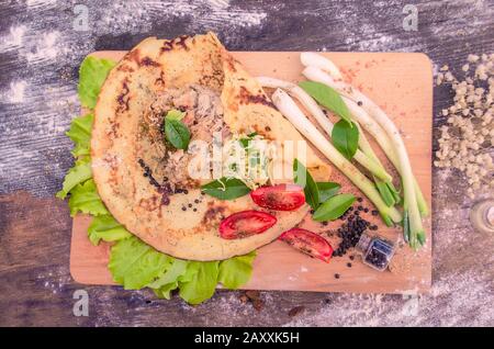 Shawarma dans du pain pita mince avec du poulet et des légumes sur une table en bois Banque D'Images