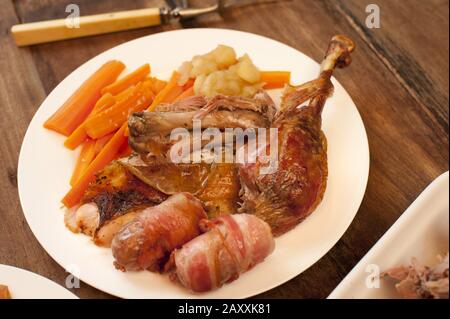 Délicieux dîner de dinde rôtie plaquée avec légumes pour fêter Noël ou Thanksgiving dans une vue rapprochée sur une table en bois Banque D'Images