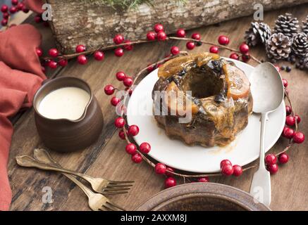 Délicieux pudding aux prunes de Noël maison avec sauce au brandy et baies rouges festives colorées sur la table Banque D'Images