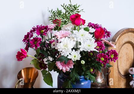 Un arrangement floral à l'intérieur comprenant des roses rouges et des chrysanthèmes roses et blancs en hiver au Royaume-Uni Banque D'Images
