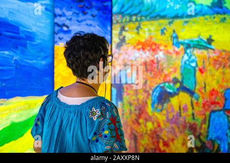 Femme avec casque sur l'écoute de l'audioguide, regardant les peintures projetées sur les murs, Rencontre Vincent van Gogh Experience 2020, Londres, Royaume-Uni Banque D'Images